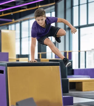 Boy vaulting over a padded box in a parkour class