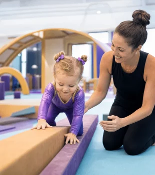 Coach guiding a young girl across a low balance beam