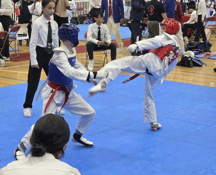 Taekwondo sparring match with a high kick at a tournament