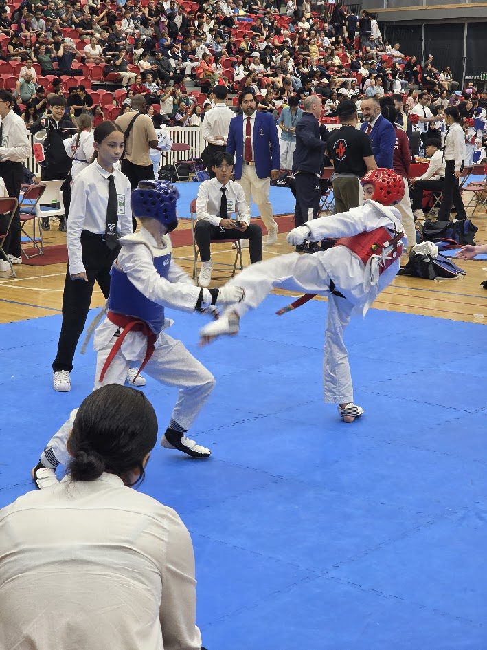 Taekwondo sparring match with a high kick at a tournament