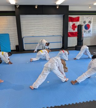 Young taekwondo students doing floor exercises during class in Rockland