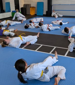 Taekwondo students stretching in a line during warm-up at The RAZ