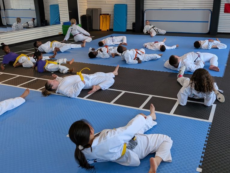 Taekwondo students stretching in a line during warm-up at The RAZ