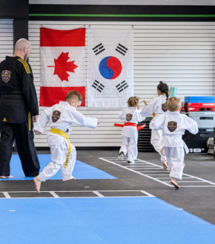 Taekwondo class lined up in front of the Canadian and Korean flags at The RAZ