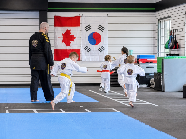 Taekwondo class lined up in front of the Canadian and Korean flags at The RAZ