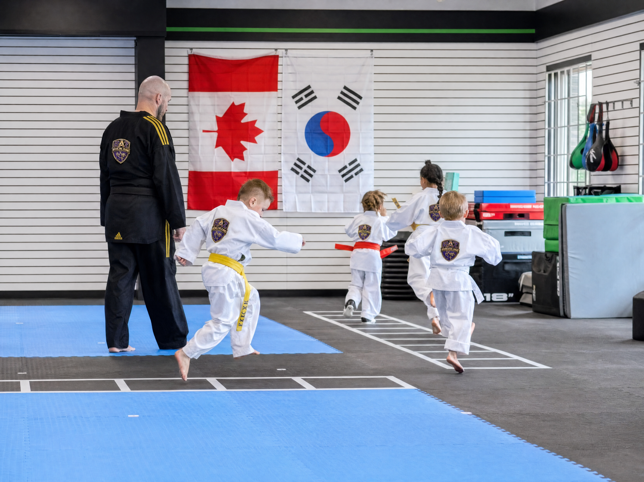 Taekwondo class lined up in front of the Canadian and Korean flags at The RAZ