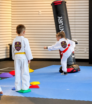 Kids practising strikes on a punching bag during a taekwondo drill