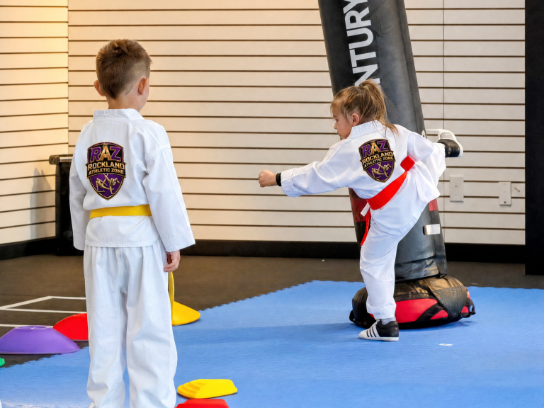 Kids practising strikes on a punching bag during a taekwondo drill
