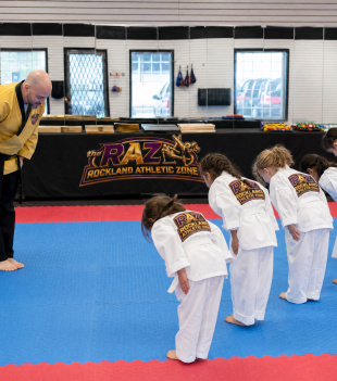 Instructor and young students bowing at the start of a taekwondo class