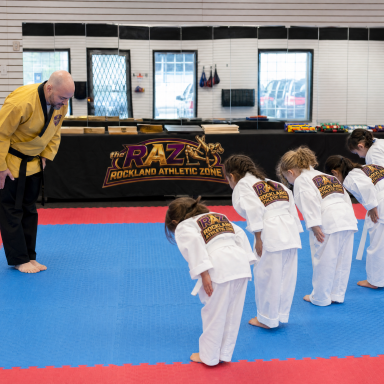 hf_20260616_060516_5c43975f-fa35-4766-ad83-97da6d4b54ce Instructor and young students bowing at the start of a taekwondo class