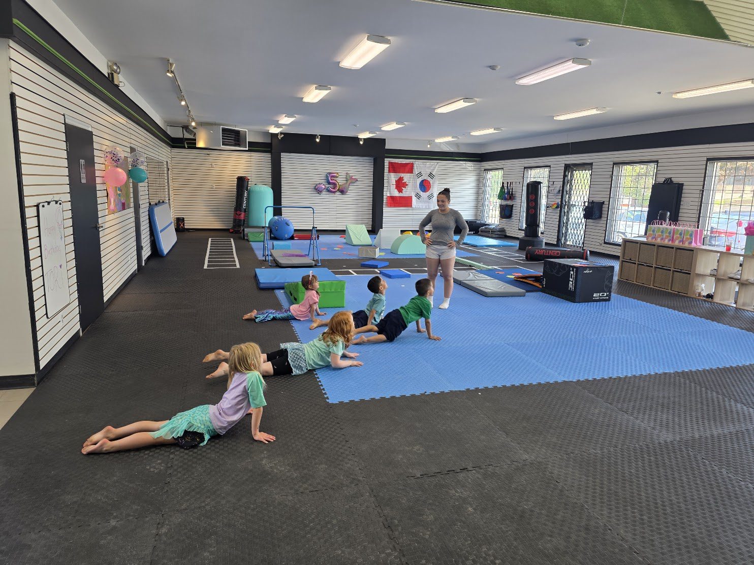 Young gymnasts stretching on the blue floor with their coach at The RAZ