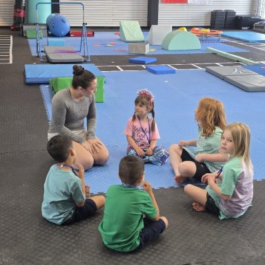 Kids Gymnastics Class at The RAZ Rockland Gymnastics coach talking with a circle of children on the mats at The RAZ