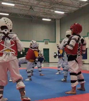 Taekwondo athletes sparring in helmets and chest guards