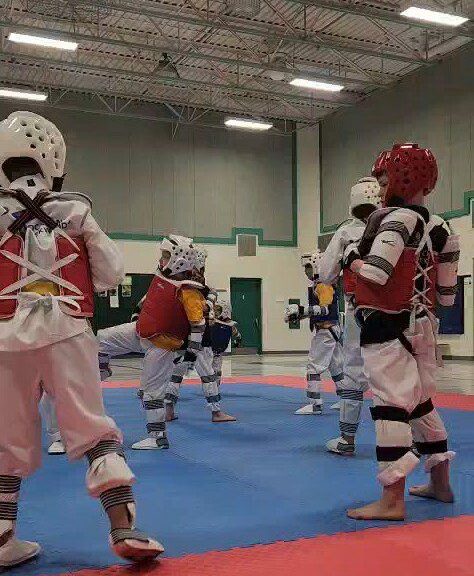 Taekwondo athletes sparring in helmets and chest guards