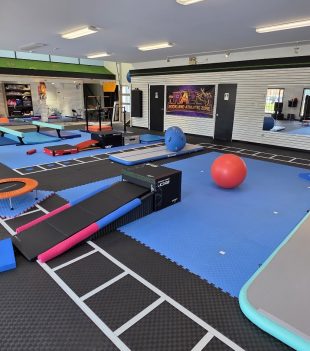 Gymnastics floor at The RAZ set up with balance beams, mats and an exercise ball